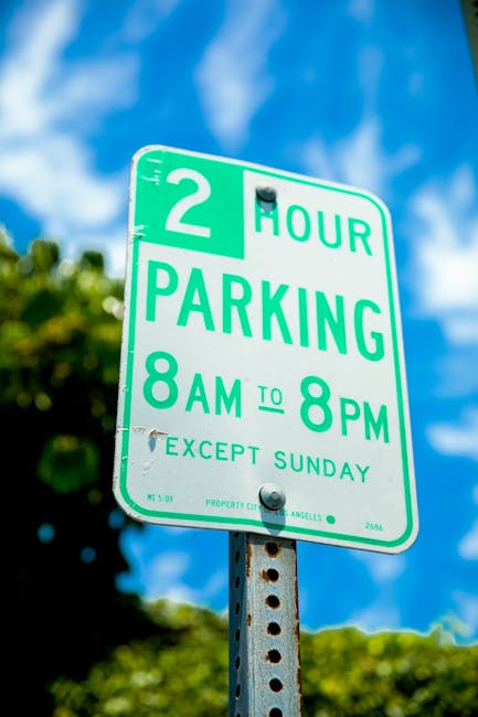 Close-up view of a rectangular white metal sign with black text stating 'PARKING WITH HOTEL PERMIT ONLY', mounted on a textured brown stone wall. The sign is secured with four screws, one at each corner. In the background, part of a street or driveway area can be seen, suggesting the location is adjacent to a building entrance or parking area. This image relates to house removals and moving services, highlighting parking permit considerations for home relocation or furniture transport—an aspect managed by companies like Man With a Van Bickley when planning local moves and ensuring proper parking arrangements.